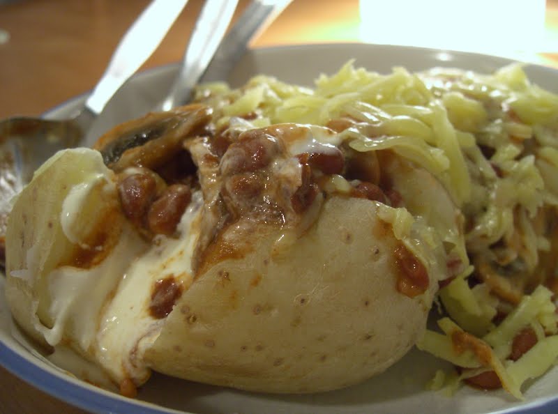 Microwaved potatoes (they can also be baked in foil over a fire or in the oven), with toppings: sour cream (partly melted at the front), spicy Mexican beans, mushrooms and grated cheese. ? Photo by me (w:User:pfctdayelise), CC BY-SA 2.5, via Wikimedia Commons