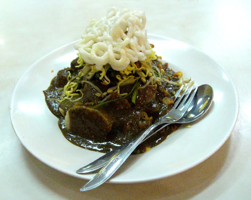 Rujak Cingur (Javanese: mouth rojak), varient of en:rujak specialty of en:Surabaya, en:East Java, en:Indonesia. Made from cooked en:buffalo snout, bengkuang (Pachyrhizus erosus), young en:mango, kangkung (water spinach or Ipomoea aquatica), en:pineapple, en:cucumber, tauge (beansprouts), lontong (glutinous rice cake), en:tofu, en:tempe, served in black sauce made from petis (black fermented shrimp paste, similar to en:terasi), and grinded peanuts, topped with sprinkle of fried shallots and krupuk (shrimp cracker). ? Photo by Gunkarta at English Wikipedia, CC BY 3.0, via Wikimedia Commons