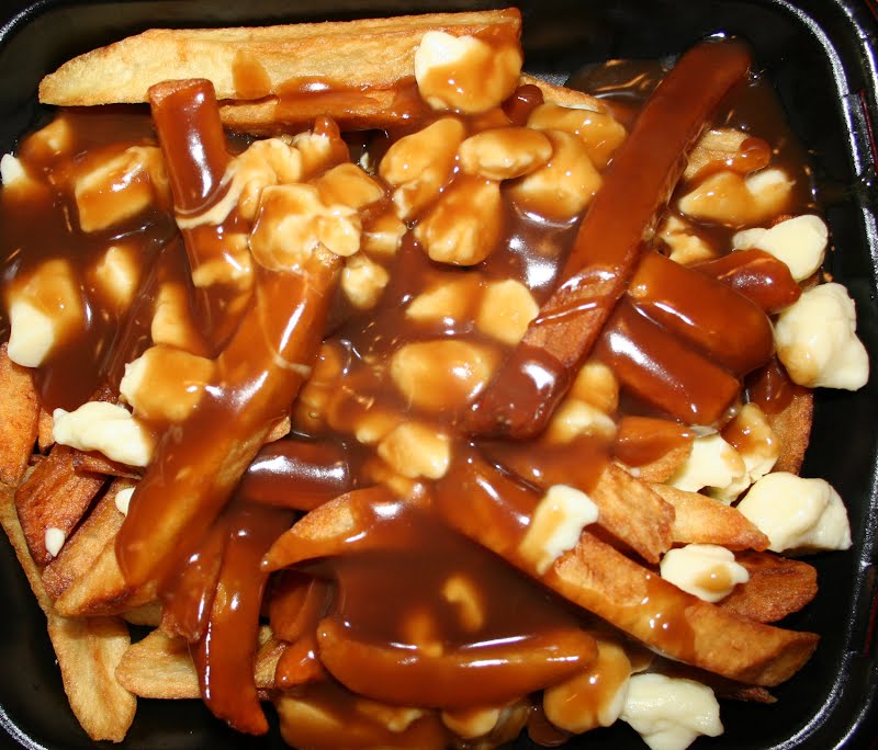 Poutine (French fried potatoes with cheese curds and beef gravy) as served at the Frit-O-Cheezz restaurant in Andover, Minnesota, United States ? Photo by Jonathunder, GFDL 1.2, via Wikimedia Commons