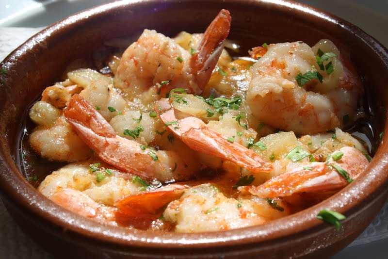 Gambas al ajillo, plato típico de la gastronomía española. Elaborado en el Restaurante La Vieja, en Adeje, Canarias. Ver artículo en el blog ellaboratoriogastronomico ? Photo by Javier Lastras from España/Spain, CC BY 2.0, via Wikimedia Commons