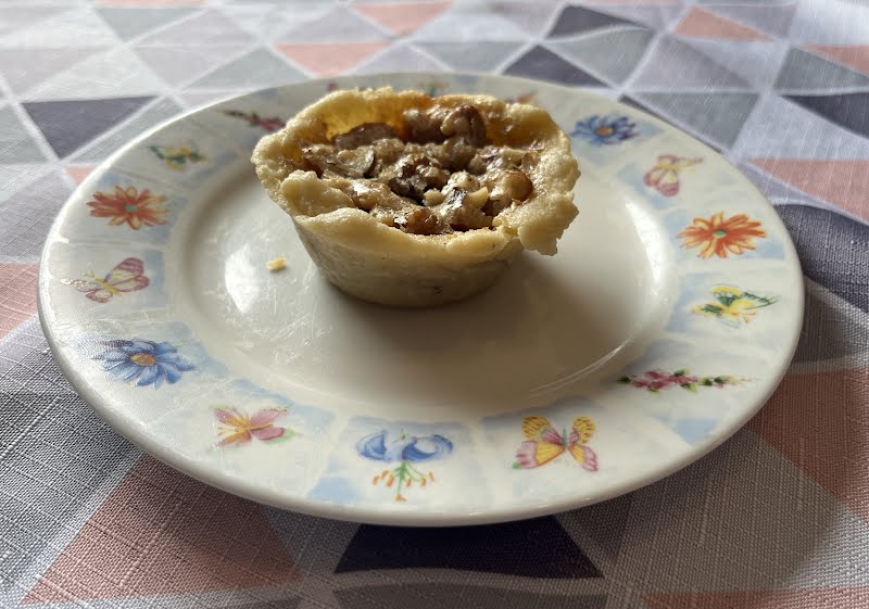 A maple butter tart topped with walnuts served on a plate. ? Photo by Cnrowley, CC BY-SA 4.0, via Wikimedia Commons